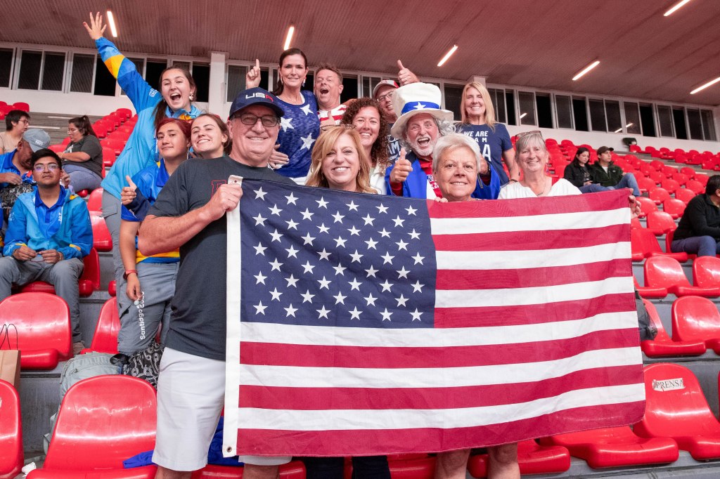 Several Team USA fans in the stands pose and hold up a U.S. flag on Tuesday in the Polideportivo, where men's and women's basketball is played.