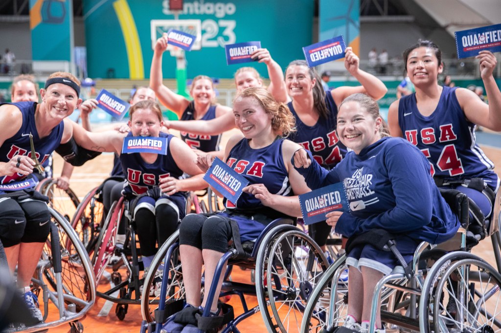 Team USA poses for a picture holding signs that say "Qualified" because it qualified for the Paris 2024 Paralympics. 