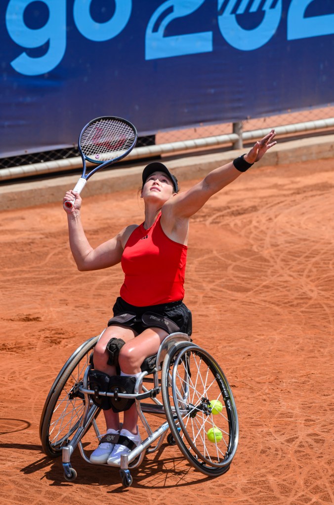 Dana Mathewson looks up and serves the tennis ball with her racquet. 