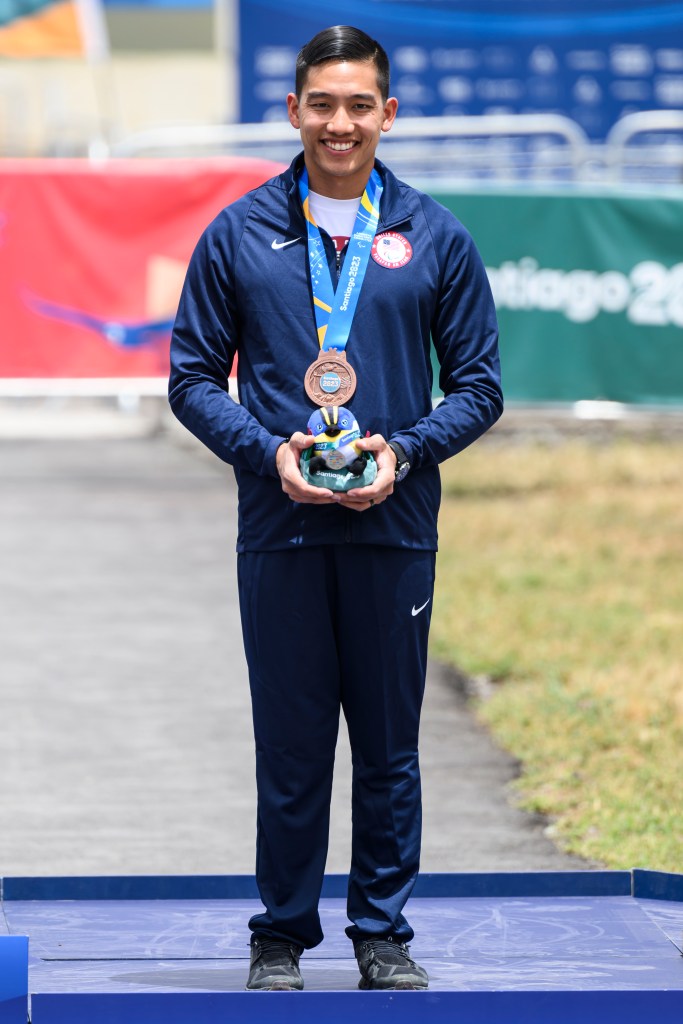 Kevin Nguyen smiles with his bronze medal around his neck, holding a mini-stuffed mascot. 