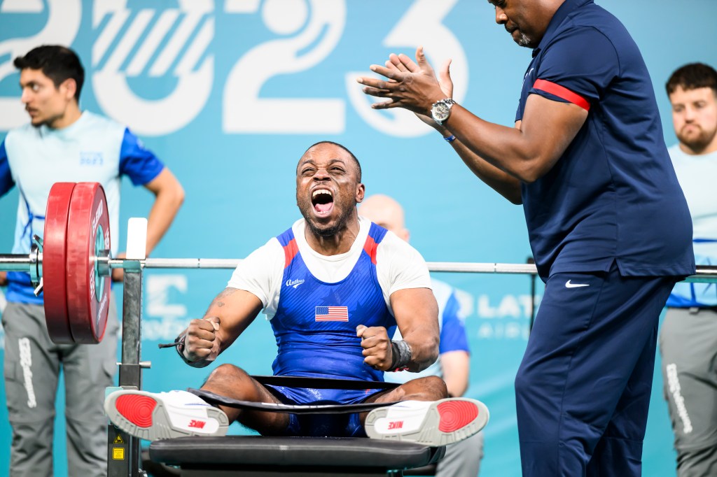 Garrison Redd, center, screams with emotion with a barbell behind him.