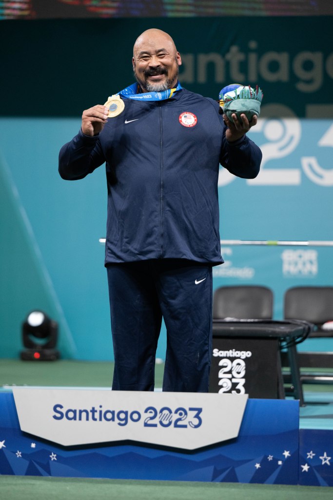 Bobby Body holds his gold medal while standing on the podium. 