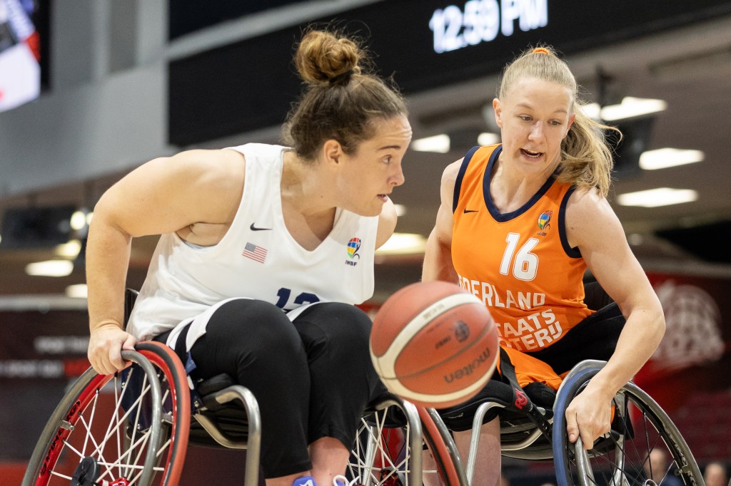 Two female wheelchair basketball players competing for the ball during a game.